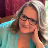Marie Ysais seated with her hand to her cheek, wearing a teal blouse