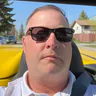 Michael Chrest wearing sunglasses, seated in a yellow convertible