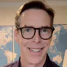 Peter M in glasses, photographed at his desk in front of a world map